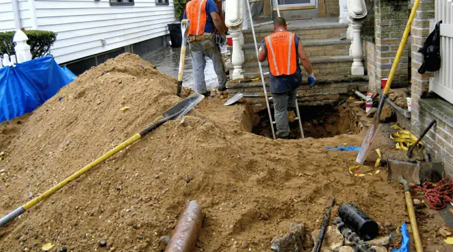 Contractors performing foundation protection and exterior drainage excavation near residential home steps in Sarasota, FL