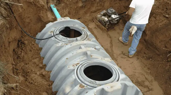 Septic tank installation showing a technician compacting soil around a new poly septic tank in an excavation pit in Sarasota, FL